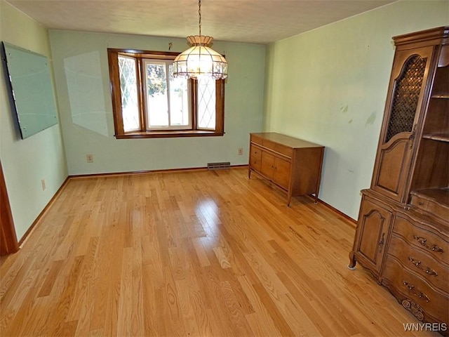 unfurnished dining area featuring baseboards, visible vents, and light wood-type flooring