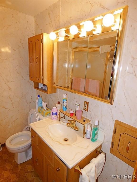 bathroom featuring vanity, tile walls, and toilet