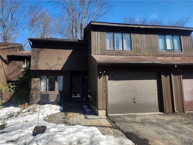 view of front of home with aphalt driveway, an attached garage, and roof with shingles