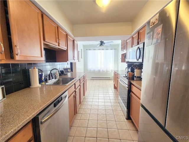 kitchen featuring light tile patterned floors, backsplash, a sink, stainless steel appliances, and baseboard heating