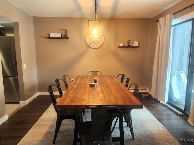 dining room with a baseboard heating unit, baseboards, and wood finished floors