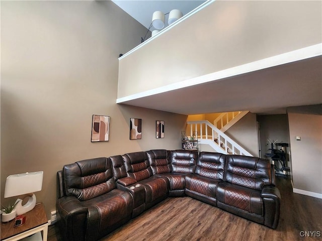 living area with stairs, a high ceiling, wood finished floors, and baseboards