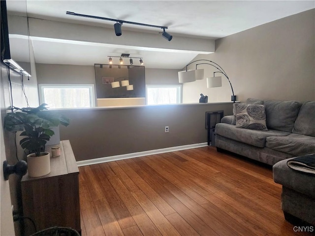 living room with lofted ceiling with beams, baseboards, wood-type flooring, and rail lighting