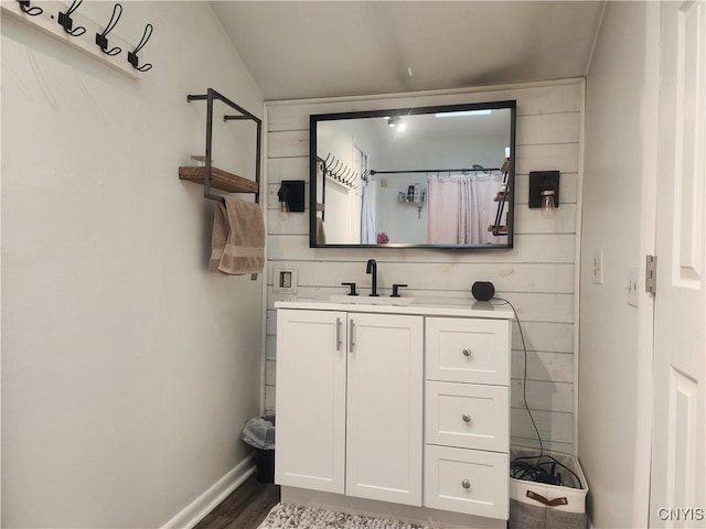 bathroom featuring a shower with curtain, vanity, baseboards, and wood finished floors