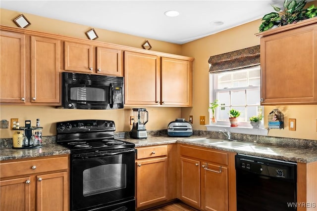 kitchen with dark countertops, black appliances, and a sink