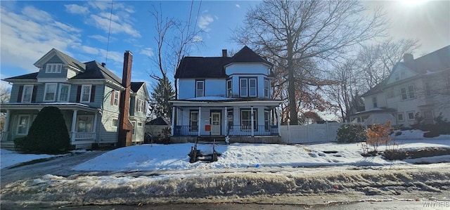 victorian house featuring a porch and fence