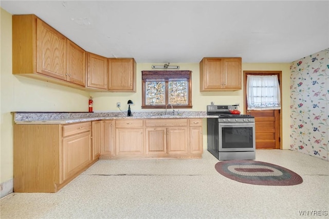 kitchen featuring a sink, stainless steel range with gas cooktop, a healthy amount of sunlight, and light countertops