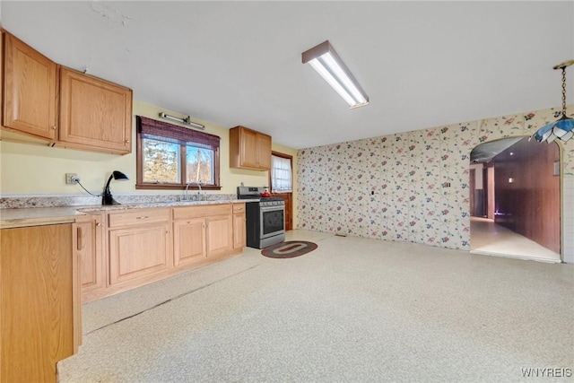 kitchen with wallpapered walls, light countertops, a sink, and stainless steel gas range oven