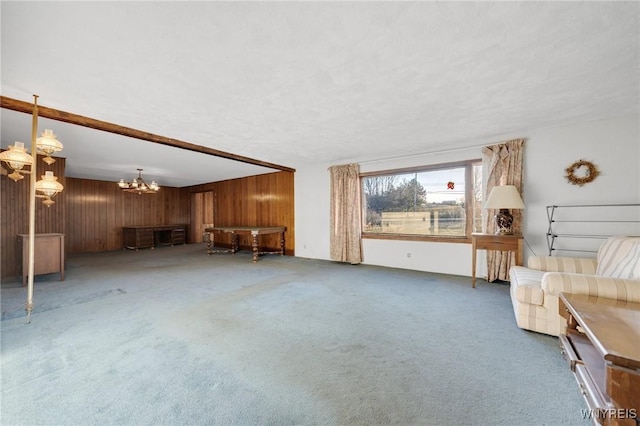 unfurnished living room with a chandelier, carpet flooring, wood walls, and a textured ceiling