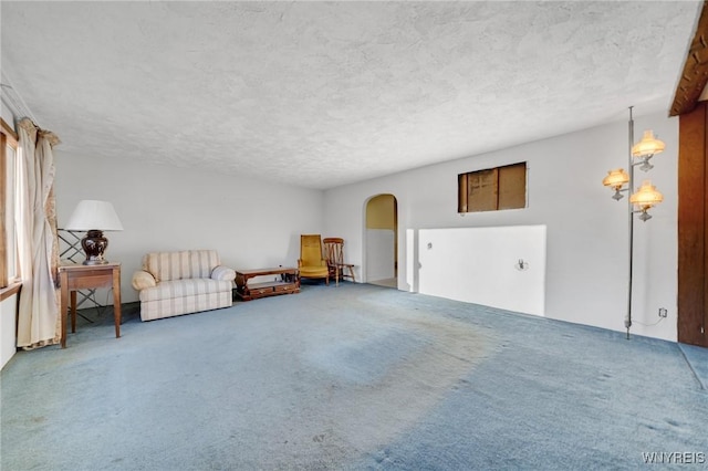 living area featuring arched walkways, carpet flooring, and a textured ceiling