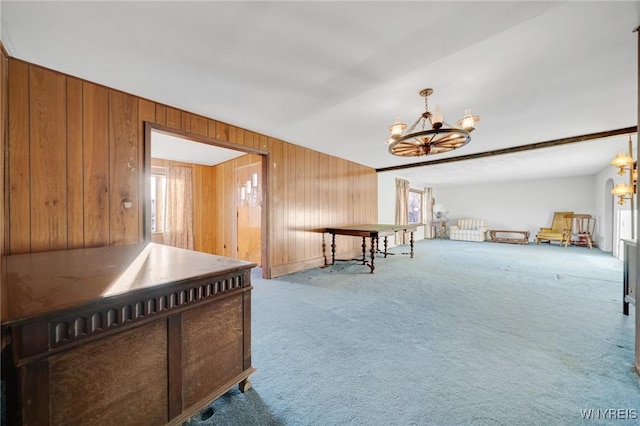 interior space with beamed ceiling, a notable chandelier, carpet, and wood walls