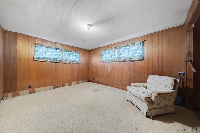 sitting room with carpet floors, a textured ceiling, and wooden walls