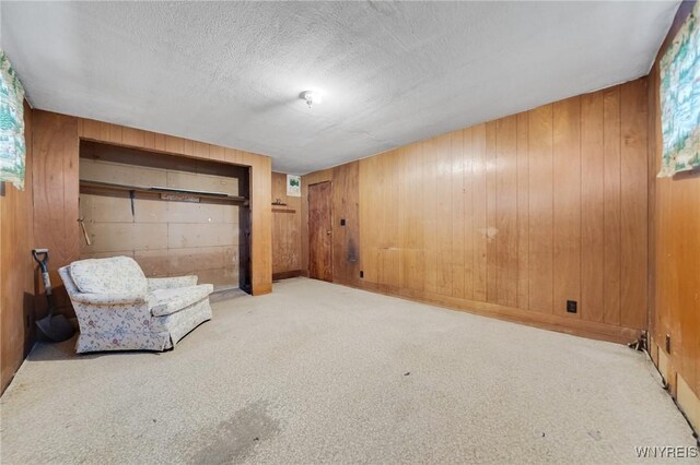 unfurnished room with a textured ceiling, wood walls, and carpet flooring