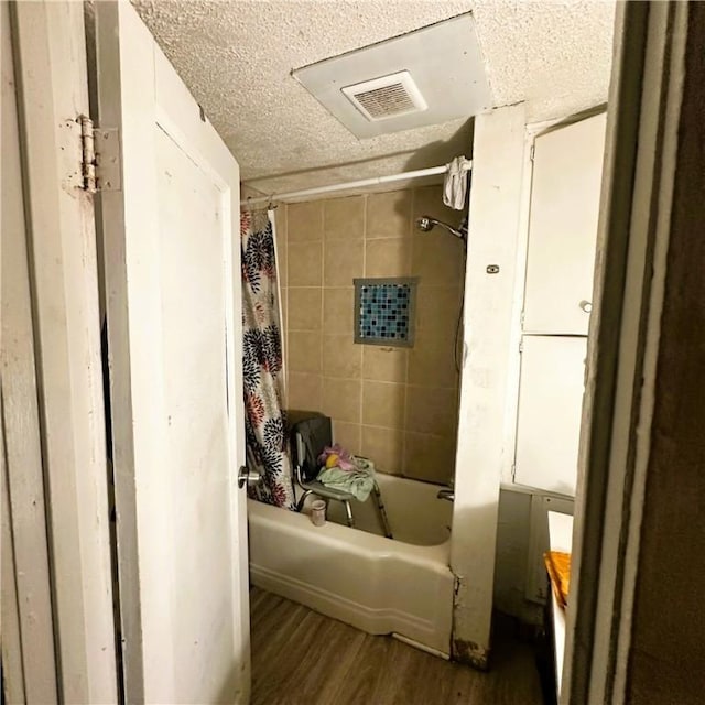 full bathroom featuring visible vents, a textured ceiling, shower / tub combo with curtain, and wood finished floors