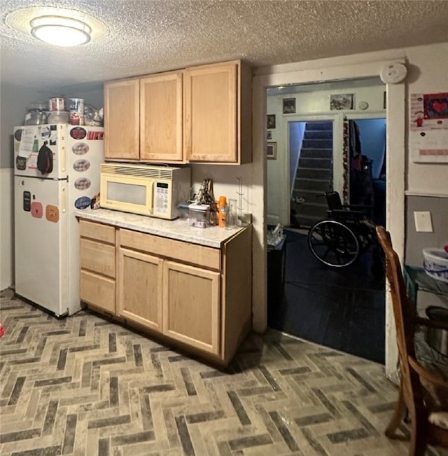 kitchen with white appliances, a textured ceiling, light brown cabinetry, and light countertops