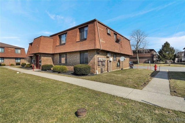 view of front of house with a front yard, mansard roof, and brick siding