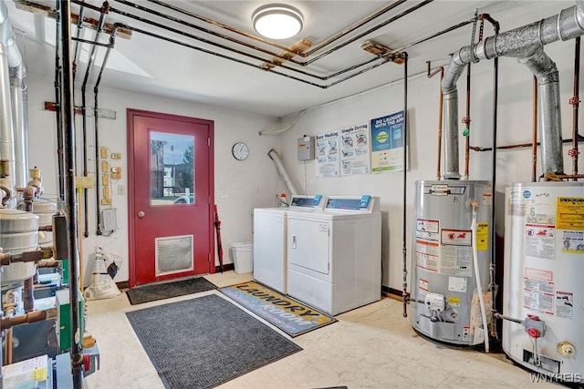 clothes washing area featuring gas water heater, visible vents, separate washer and dryer, and laundry area