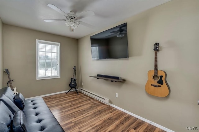 interior space featuring ceiling fan, a baseboard heating unit, baseboards, and wood finished floors