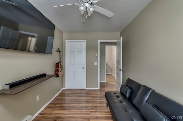 living area featuring ceiling fan, baseboards, and wood finished floors