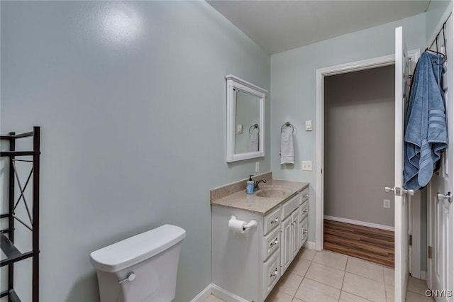 bathroom with tile patterned flooring, toilet, vanity, and baseboards