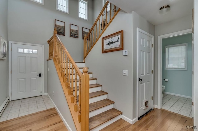 entryway with stairs, baseboards, light wood-type flooring, and baseboard heating