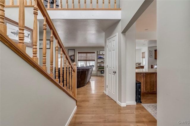 foyer entrance with baseboards, baseboard heating, stairs, and light wood finished floors