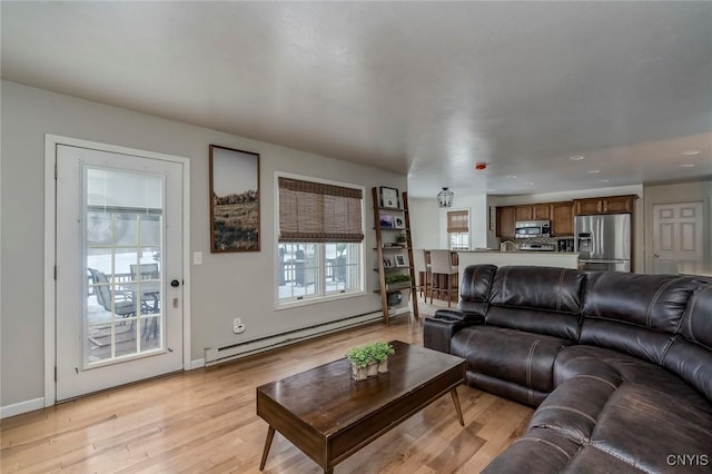 living room featuring a baseboard radiator, baseboards, and light wood-style floors