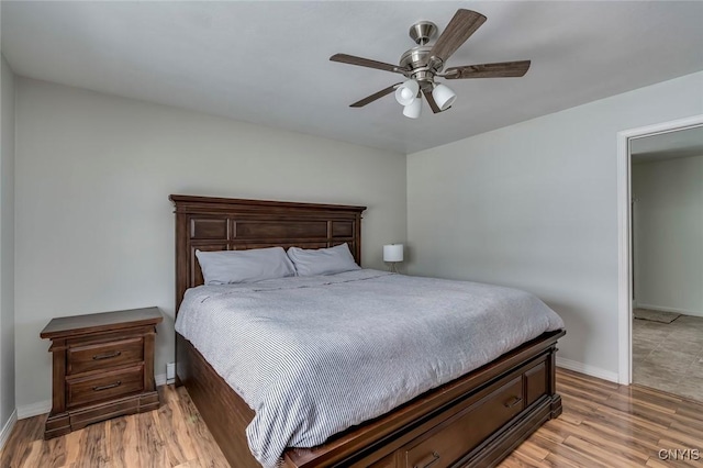 bedroom with a ceiling fan, baseboards, and light wood-type flooring