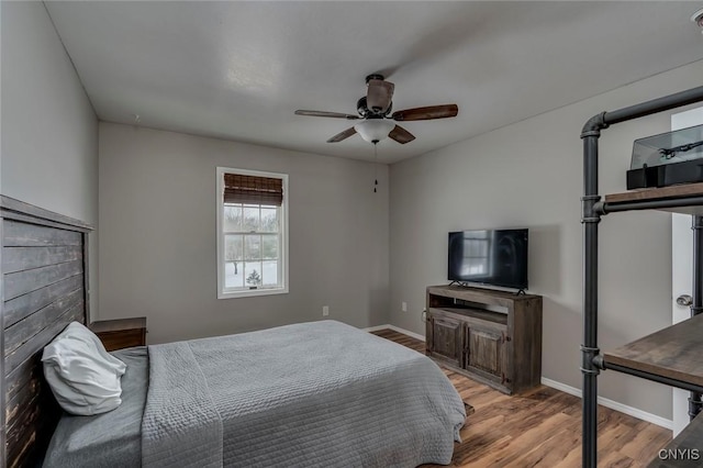 bedroom featuring ceiling fan, baseboards, and wood finished floors