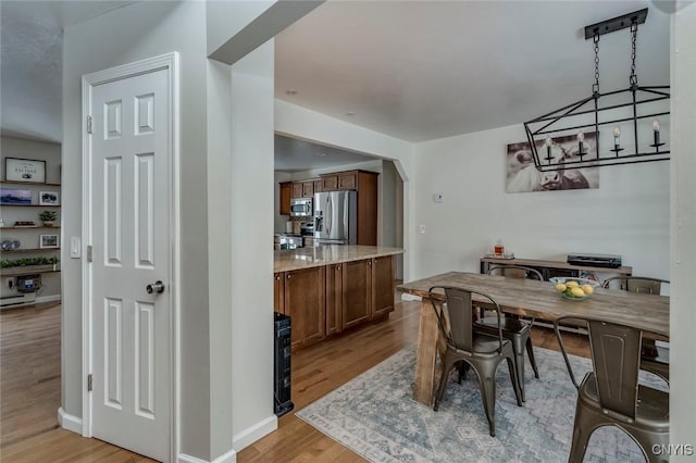 dining area with baseboards, arched walkways, and light wood-style floors