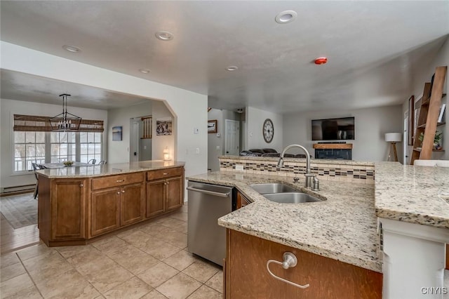 kitchen with brown cabinetry, an island with sink, a sink, dishwasher, and open floor plan