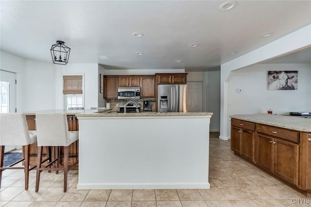 kitchen with tasteful backsplash, light stone countertops, a breakfast bar area, recessed lighting, and appliances with stainless steel finishes