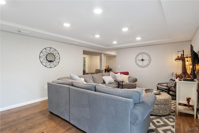 living area with a raised ceiling, recessed lighting, wood finished floors, and baseboards