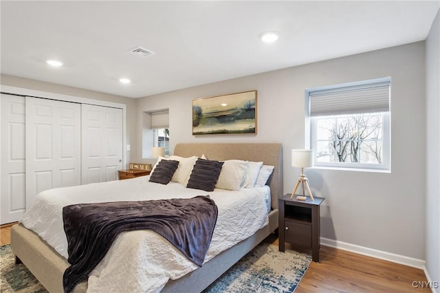 bedroom with wood finished floors, visible vents, baseboards, recessed lighting, and a closet