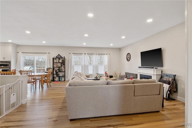 living area with recessed lighting, baseboards, light wood-style flooring, and a fireplace