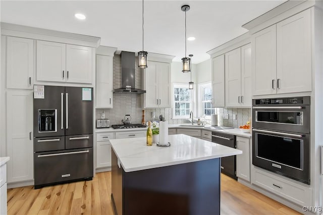 kitchen with a sink, decorative backsplash, black appliances, light countertops, and wall chimney exhaust hood