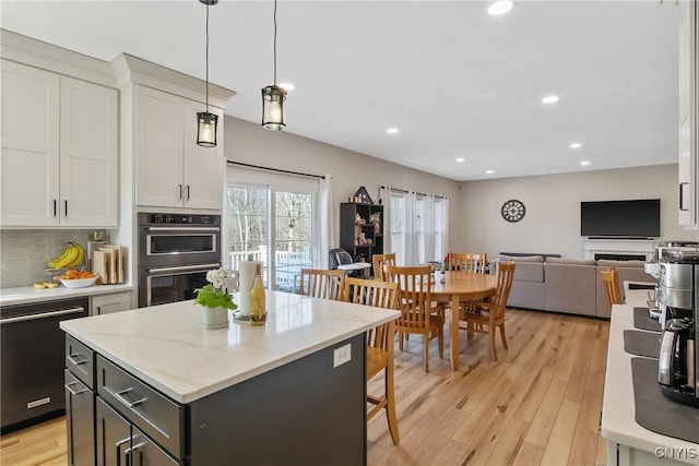 kitchen with multiple ovens, dishwashing machine, white cabinets, and light wood finished floors