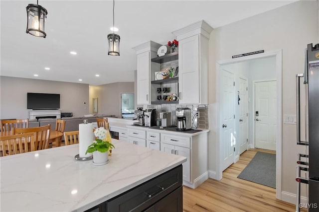 kitchen featuring open shelves, light stone counters, tasteful backsplash, light wood-style floors, and white cabinets