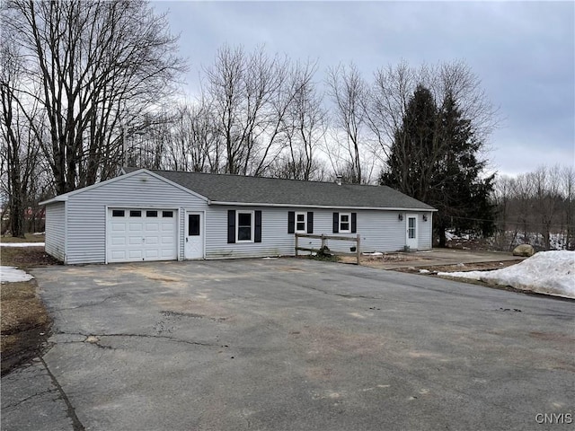 single story home with an attached garage, driveway, and a shingled roof