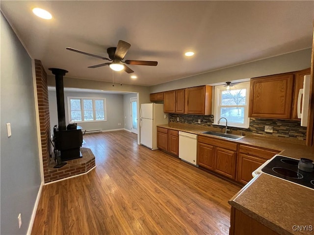 kitchen featuring white appliances, a healthy amount of sunlight, light wood finished floors, and a sink