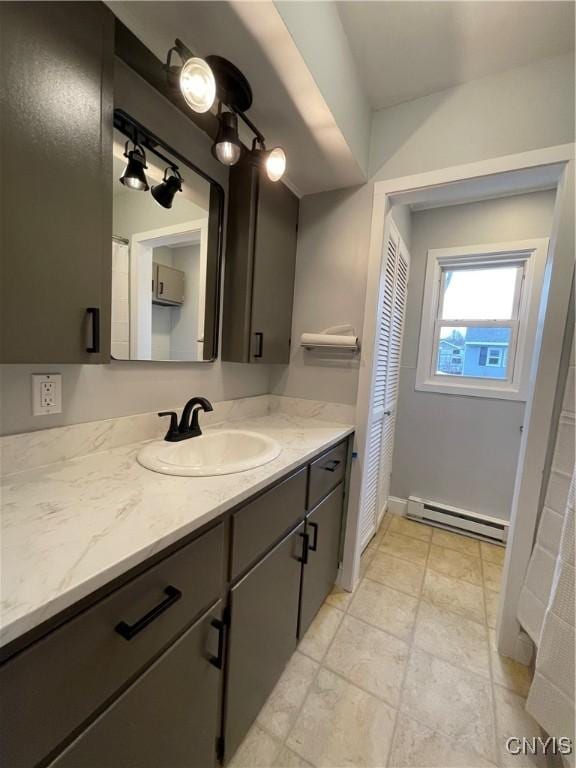 bathroom featuring a baseboard heating unit, baseboards, and vanity