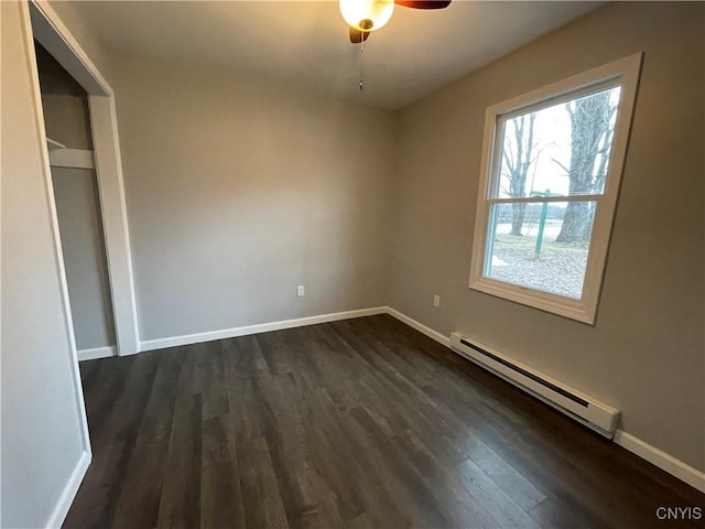 unfurnished bedroom with ceiling fan, a baseboard radiator, baseboards, and dark wood-style floors