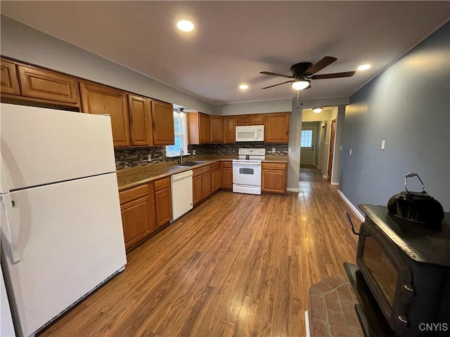 kitchen with decorative backsplash, brown cabinets, white appliances, and wood finished floors