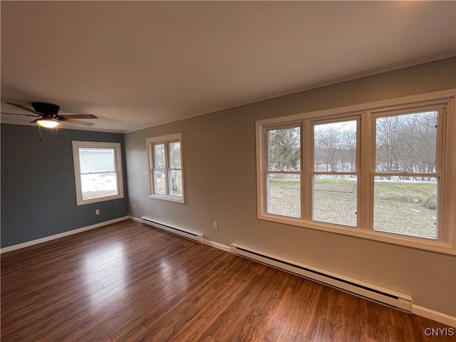 spare room with a baseboard radiator, baseboards, dark wood-type flooring, and ceiling fan