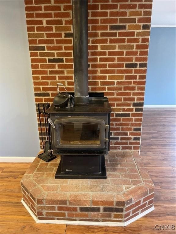 room details with a wood stove, baseboards, and wood finished floors