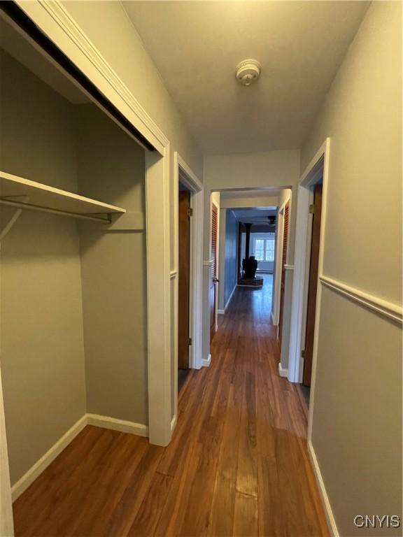 corridor featuring dark wood-type flooring and baseboards