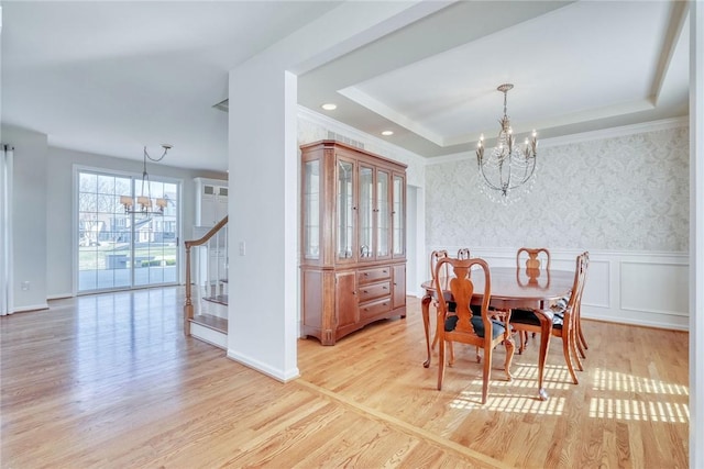 dining room featuring a chandelier, wainscoting, wallpapered walls, and a raised ceiling