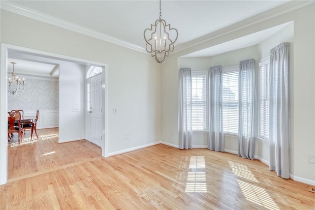 spare room featuring a notable chandelier, wood finished floors, baseboards, and ornamental molding