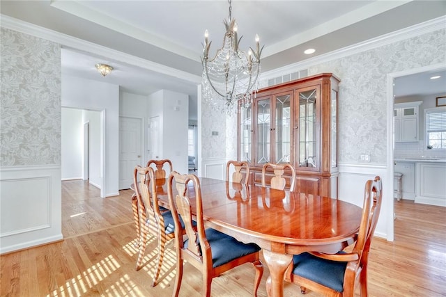 dining area with a chandelier, wainscoting, wallpapered walls, and light wood-style flooring