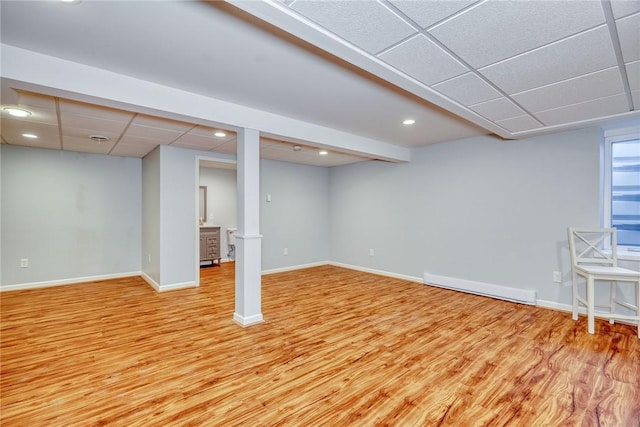 finished below grade area featuring baseboards, light wood-type flooring, and a drop ceiling